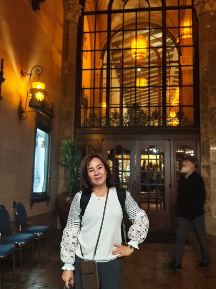 冠昀背著包包出門玩，站在一棟漂亮的老建築前面